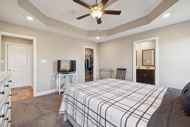 bedroom with ceiling fan, a walk in closet, a closet, and a raised ceiling