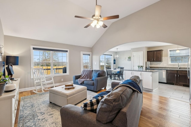 living room featuring light wood-type flooring, ceiling fan, sink, and lofted ceiling