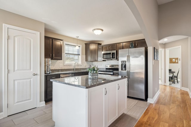 kitchen featuring decorative light fixtures, appliances with stainless steel finishes, a center island, and dark brown cabinets