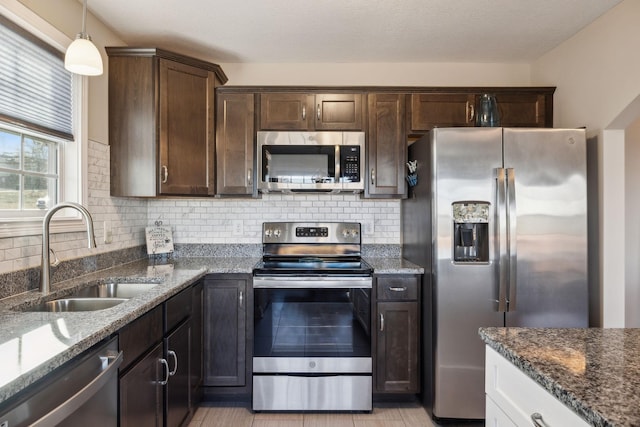 kitchen with sink, tasteful backsplash, dark stone countertops, and stainless steel appliances