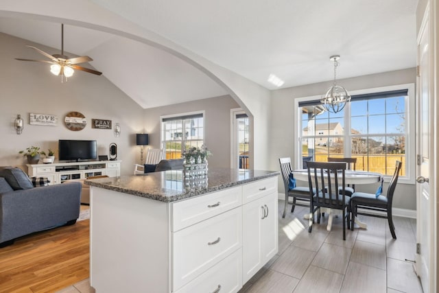 kitchen with white cabinets, a kitchen island, dark stone countertops, and plenty of natural light