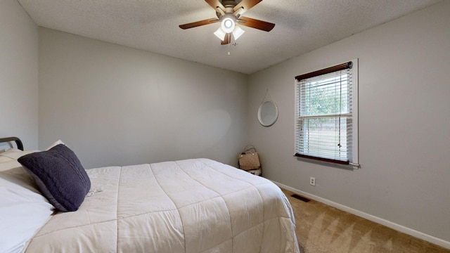 bedroom featuring a textured ceiling, ceiling fan, and light colored carpet