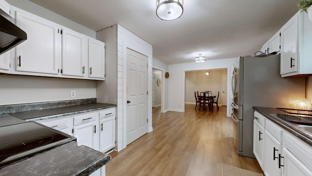 kitchen featuring range hood, white cabinetry, a textured ceiling, and light hardwood / wood-style flooring