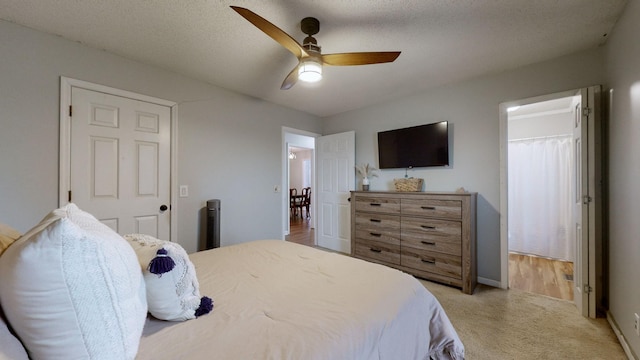 carpeted bedroom with ceiling fan and a textured ceiling