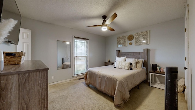 bedroom with ceiling fan, light colored carpet, and a textured ceiling