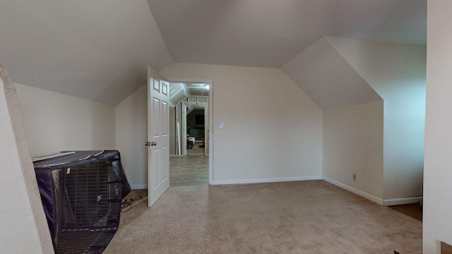 additional living space featuring light colored carpet and vaulted ceiling