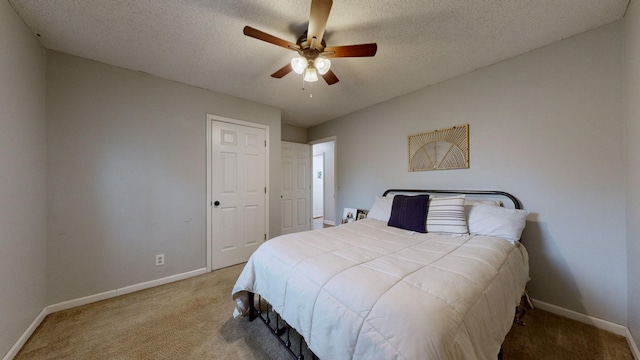 carpeted bedroom featuring ceiling fan and a textured ceiling