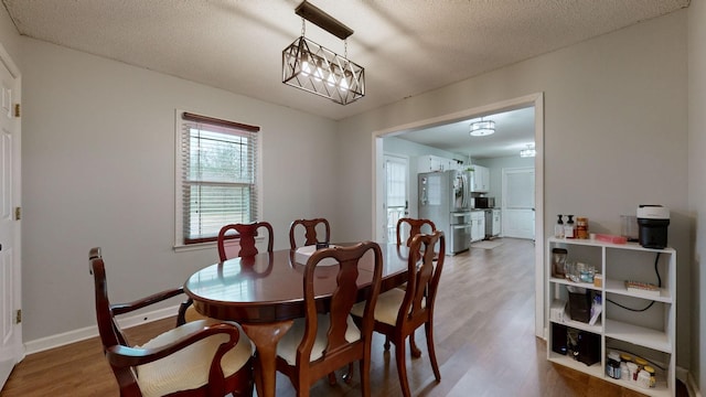 dining room with a textured ceiling, a chandelier, and hardwood / wood-style flooring