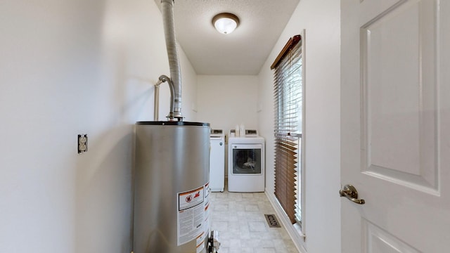 washroom with water heater, independent washer and dryer, and a textured ceiling