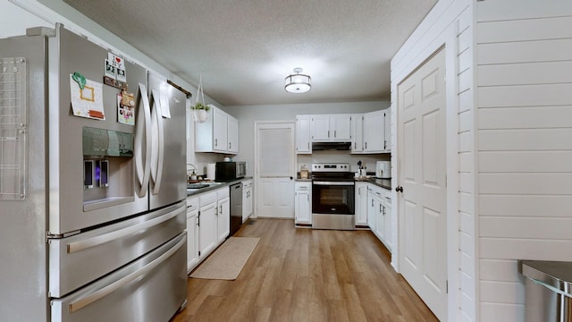 kitchen featuring white cabinetry, appliances with stainless steel finishes, a textured ceiling, and light wood-type flooring