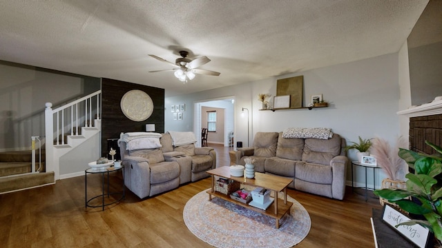 living room with hardwood / wood-style flooring, a textured ceiling, and ceiling fan