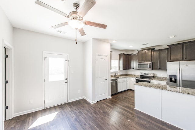 kitchen featuring sink, dark brown cabinetry, light stone countertops, appliances with stainless steel finishes, and dark hardwood / wood-style flooring