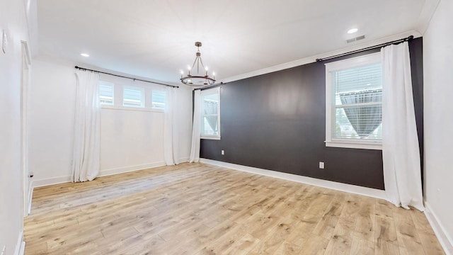 empty room with light wood-type flooring, a chandelier, and ornamental molding