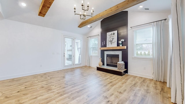 living room featuring light wood-type flooring, an inviting chandelier, vaulted ceiling with beams, and a fireplace