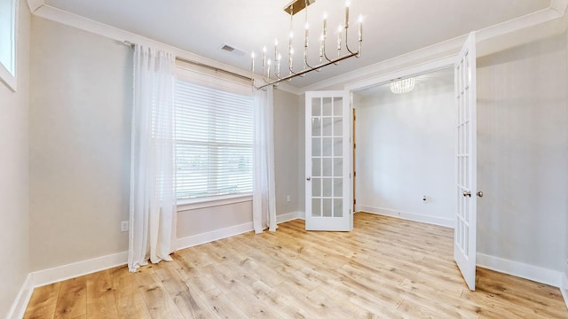 unfurnished dining area featuring french doors, an inviting chandelier, light hardwood / wood-style floors, and crown molding