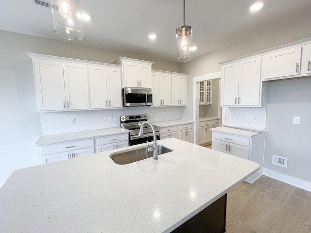 kitchen featuring white cabinetry, stainless steel appliances, tasteful backsplash, decorative light fixtures, and sink