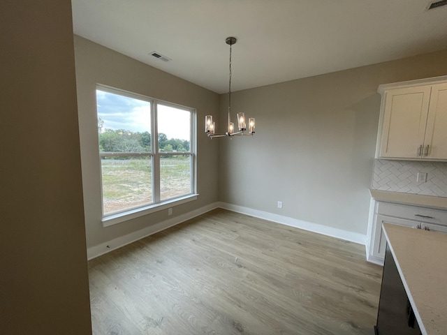 unfurnished dining area featuring a chandelier and light hardwood / wood-style floors