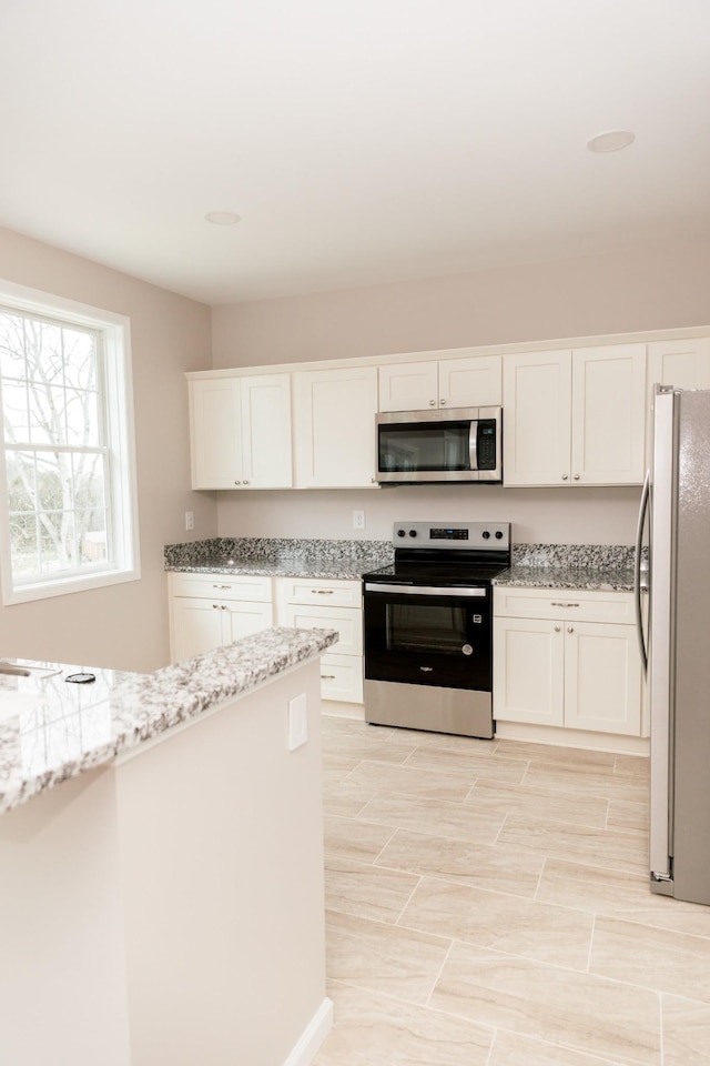 kitchen featuring white cabinets, light stone countertops, and appliances with stainless steel finishes