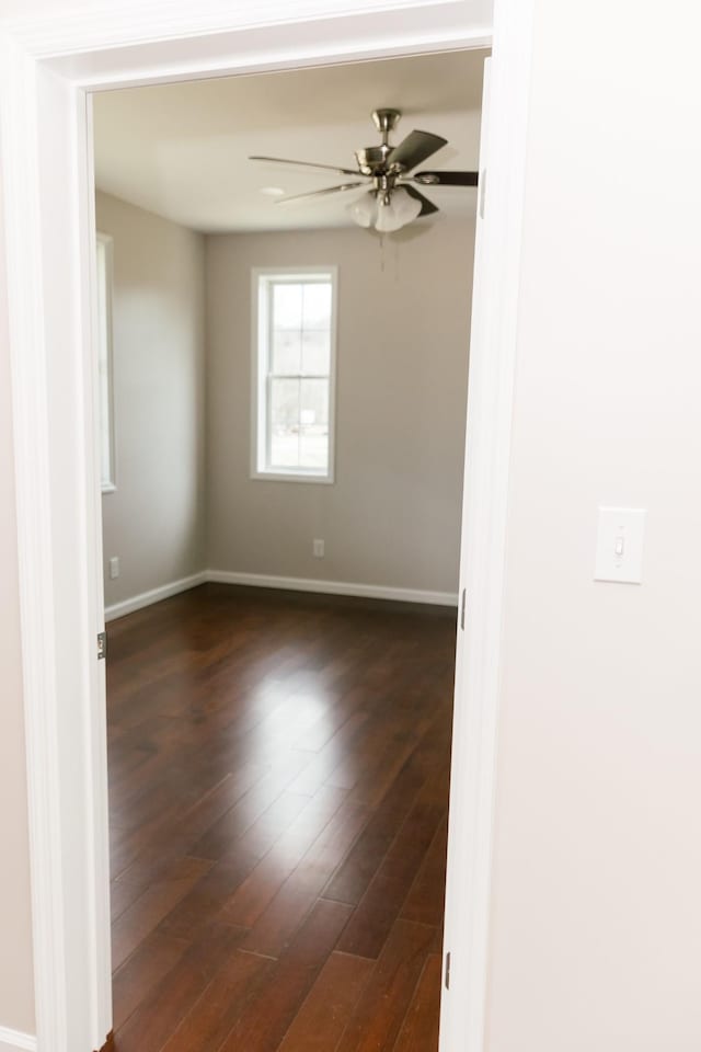 empty room with ceiling fan, baseboards, and dark wood-style floors