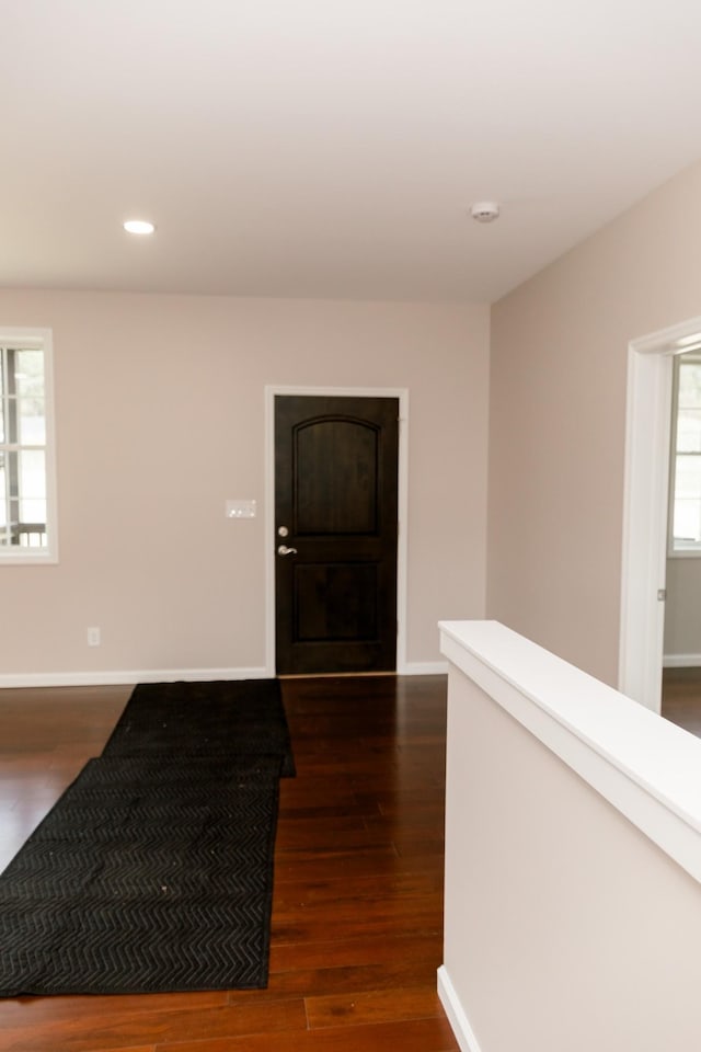 corridor featuring recessed lighting, dark wood-type flooring, and baseboards