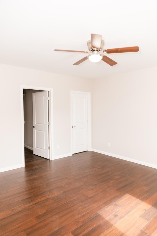 unfurnished room featuring baseboards, a ceiling fan, and dark wood-style flooring