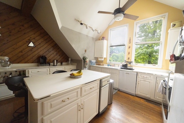 kitchen featuring a kitchen island, lofted ceiling, dishwasher, and white cabinetry