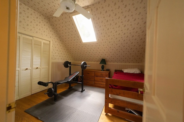 workout area featuring ceiling fan, a skylight, and light hardwood / wood-style flooring