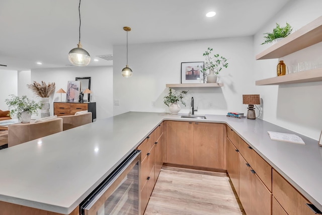 kitchen featuring wine cooler, a peninsula, a sink, light countertops, and open shelves