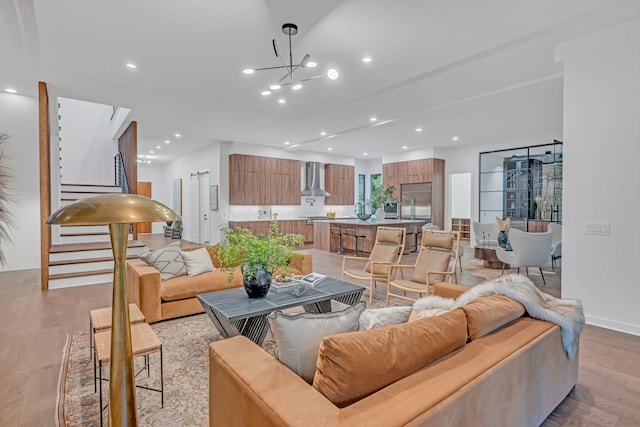 living room with baseboards, an inviting chandelier, stairs, light wood-type flooring, and recessed lighting