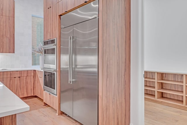 kitchen featuring stainless steel appliances, light countertops, light wood-style flooring, light brown cabinetry, and modern cabinets