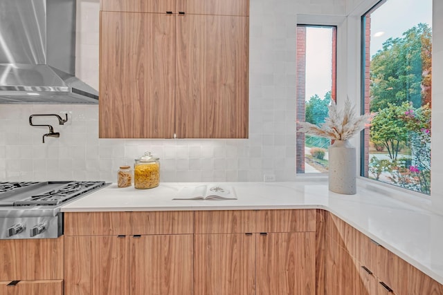 kitchen featuring wall chimney exhaust hood, modern cabinets, stainless steel gas cooktop, and tasteful backsplash