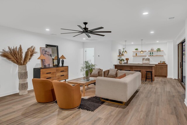 living room featuring light wood-type flooring, baseboards, a ceiling fan, and recessed lighting