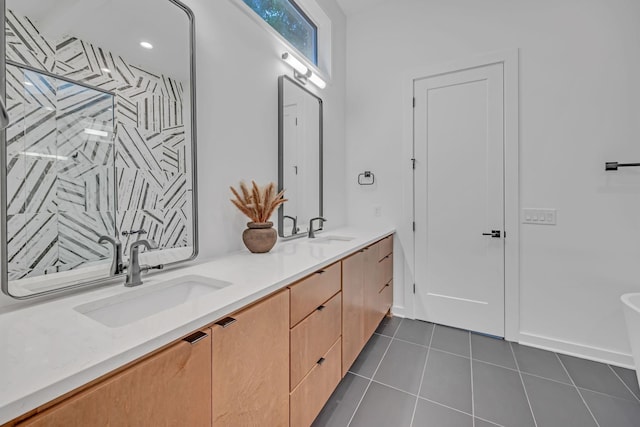 bathroom with double vanity, tile patterned flooring, a tile shower, and a sink