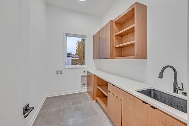 washroom featuring light tile patterned floors, washer hookup, a sink, baseboards, and cabinet space