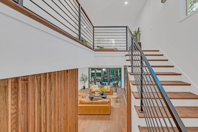 staircase with wood finished floors and a towering ceiling