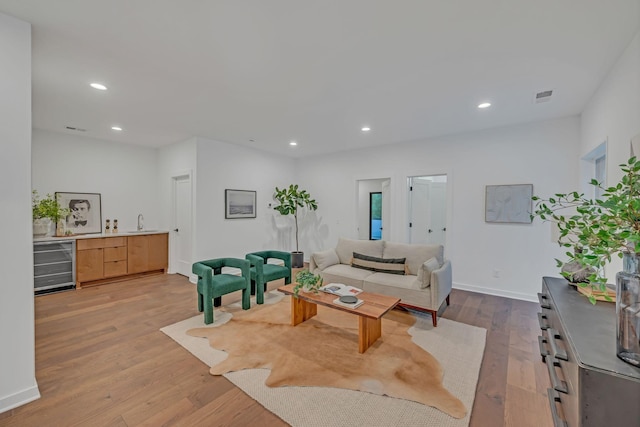 living area featuring beverage cooler, visible vents, wood finished floors, and recessed lighting