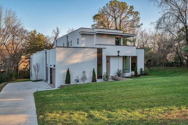 view of front of home featuring driveway, stucco siding, and a front yard