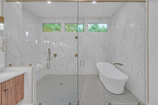 bathroom featuring a freestanding tub, a marble finish shower, tile walls, and vanity