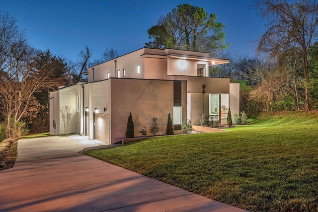 exterior space featuring concrete driveway, a front lawn, and stucco siding