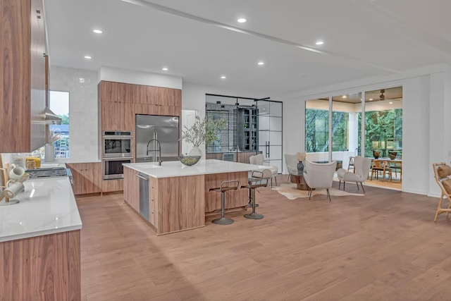 kitchen with light wood-type flooring, modern cabinets, appliances with stainless steel finishes, and light countertops