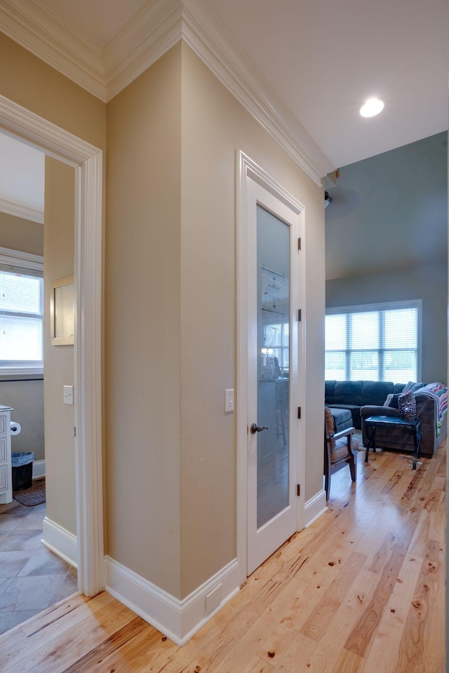 hall with light hardwood / wood-style floors and ornamental molding