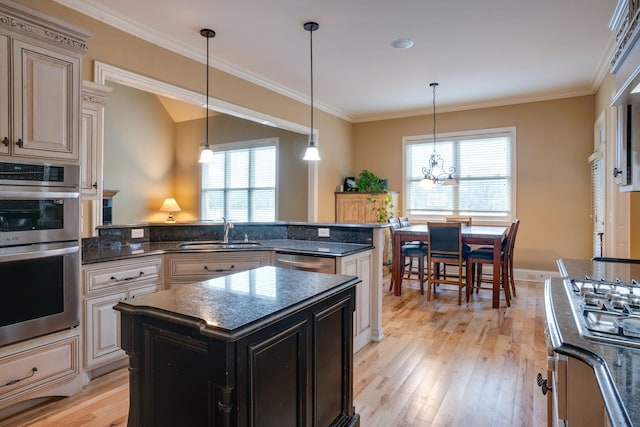 kitchen with decorative light fixtures, light hardwood / wood-style floors, a kitchen island, sink, and stainless steel appliances