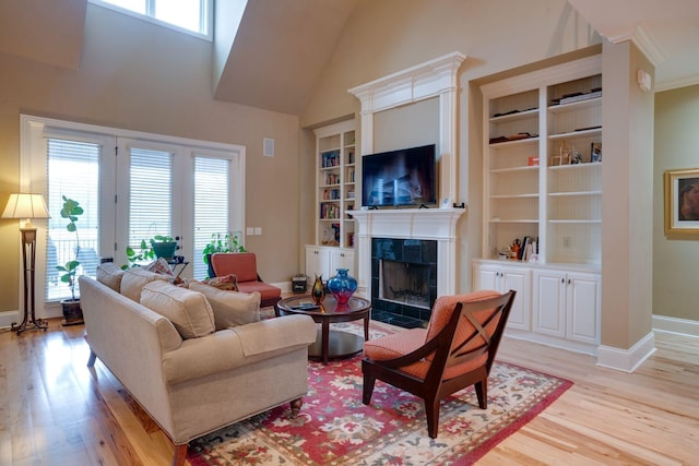 living room featuring plenty of natural light, built in shelves, a tile fireplace, and light wood-type flooring