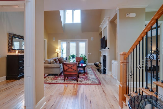 living room featuring light hardwood / wood-style floors, a high ceiling, and crown molding