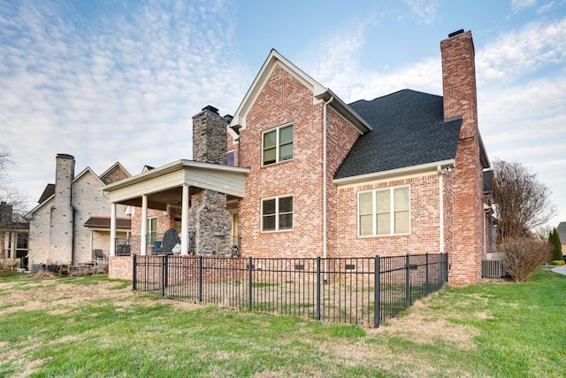 rear view of property featuring a yard and central AC unit