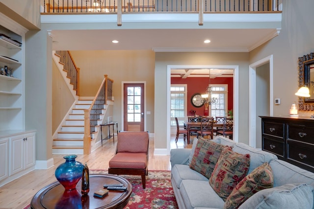 living room featuring a wealth of natural light, ornamental molding, beamed ceiling, and light wood-type flooring