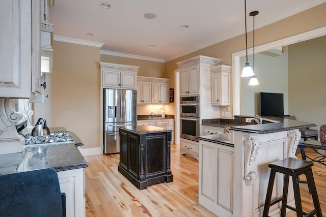 kitchen featuring appliances with stainless steel finishes, decorative light fixtures, a kitchen bar, kitchen peninsula, and light hardwood / wood-style flooring