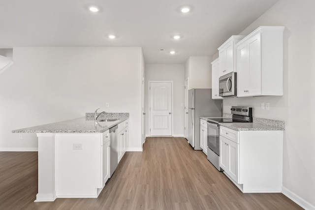 kitchen featuring sink, light hardwood / wood-style flooring, light stone countertops, stainless steel appliances, and white cabinets