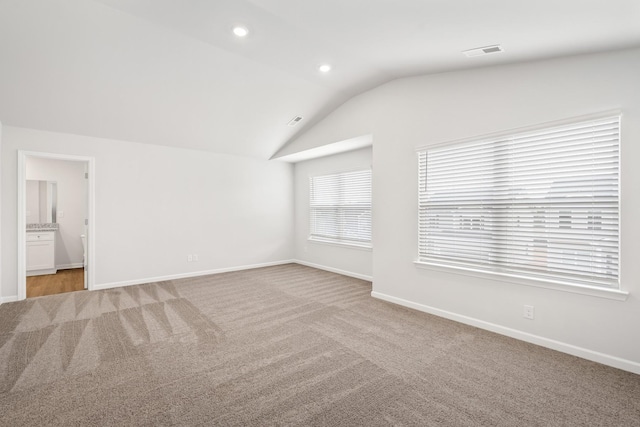 unfurnished room featuring light colored carpet and vaulted ceiling