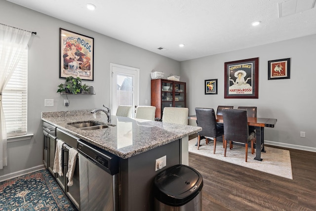 kitchen featuring dishwasher, dark wood-type flooring, sink, kitchen peninsula, and light stone counters